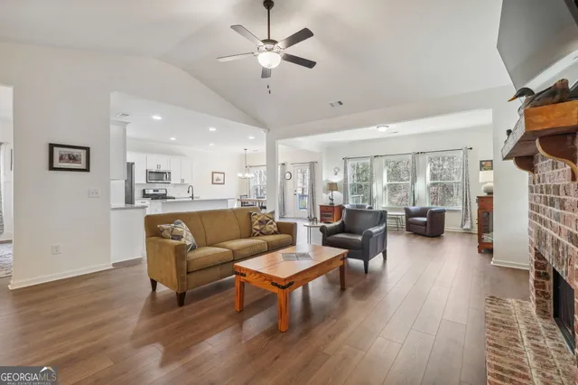 a living room with furniture kitchen view and a wooden floor
