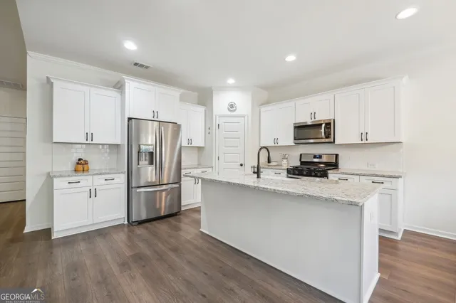 a large kitchen with granite countertop a sink and a large mirror or refrigerator