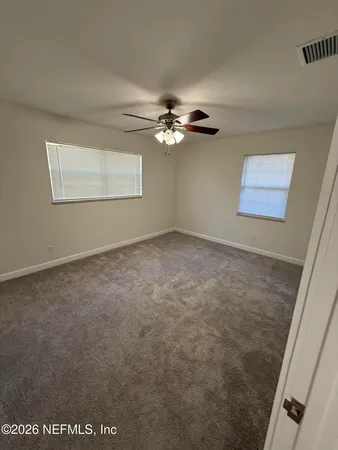 an empty room with windows and fan