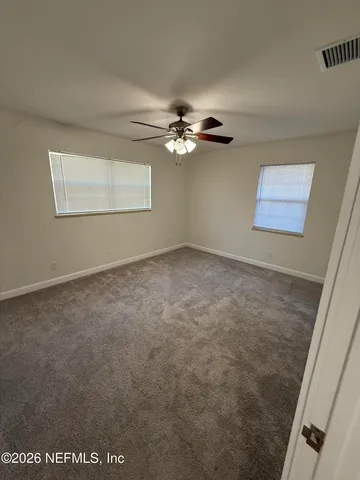 an empty room with windows and fan