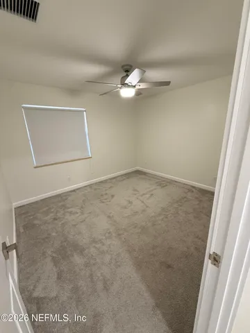 an empty room with a ceiling fan and a window