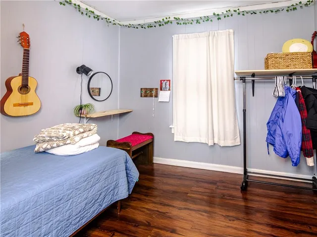 a bedroom with a bed and painting on the wooden floor