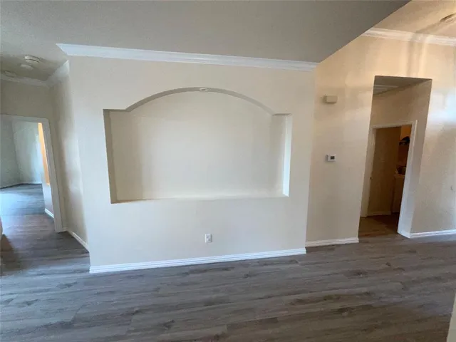 a view of an empty room with wooden floor and a fireplace