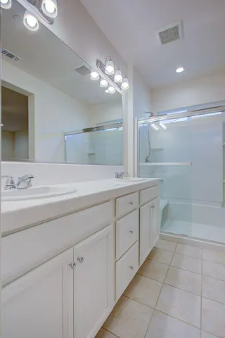 a spacious bathroom with a shower a sink and a mirror
