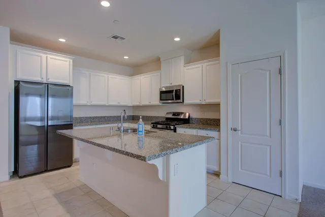 a kitchen with stainless steel appliances granite countertop a refrigerator a sink a stove a microwave and island