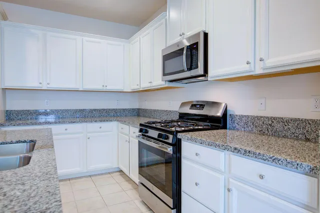 a kitchen with granite countertop white cabinets and stainless steel appliances