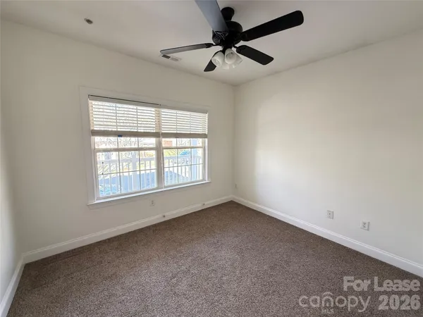 an empty room with a window and a fan