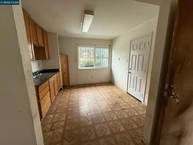 a view of a kitchen in an empty room and a window
