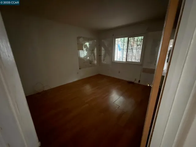 a view of an empty room with wooden floor and a window
