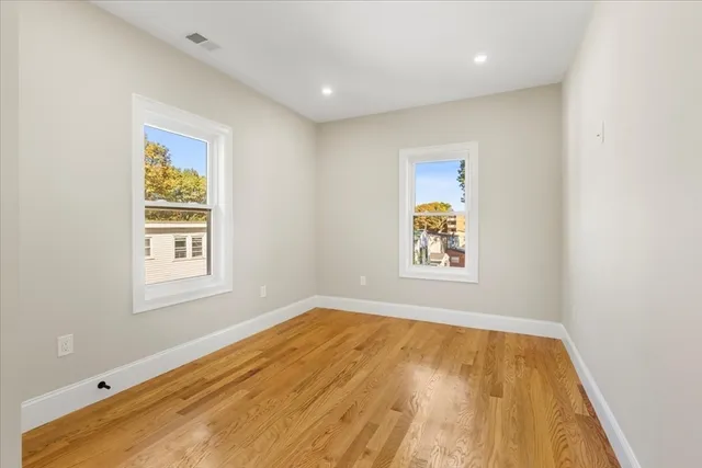 a view of an empty room with window and wooden floor