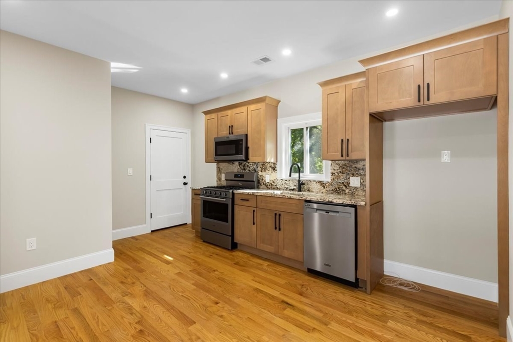 31 Woodale Avenue, Unit 2 Boston, MA 02126 - Photo 5 of 16 a kitchen with stainless steel appliances granite countertop a refrigerator sink and cabinets