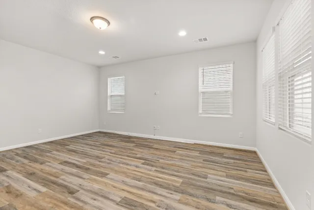 an empty room with wooden floor and windows