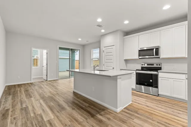 a kitchen with granite countertop a stove a sink and a refrigerator