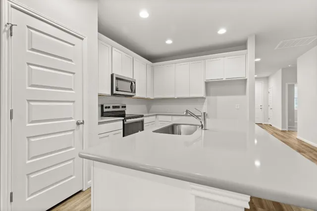 a kitchen with granite countertop white cabinets and stainless steel appliances
