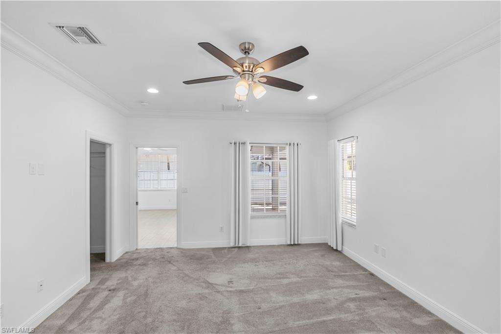 183 7th Street Naples, FL 34113 - Photo 25 of 50 Master bedroom with light carpet, a ceiling fan, crown molding, recessed lighting, and a healthy amount of natural light