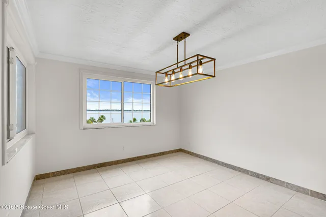 an empty room with chandelier fan and windows