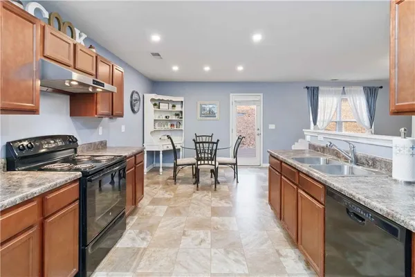 a kitchen with stainless steel appliances granite countertop a stove a sink a oven a dining table and chairs
