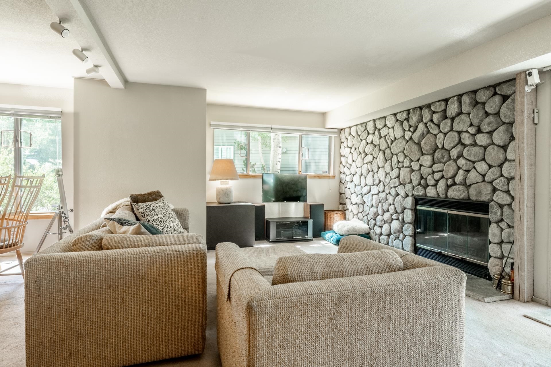 609 Golden Creek Road, Unit 609 Mammoth Lakes, CA 93546 - Photo 19 of 42 Living area featuring a floor-to-ceiling river rock fireplace, track lighting, and multiple windows