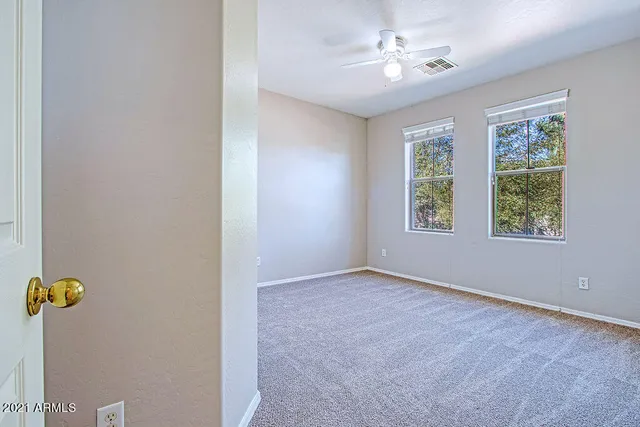 an empty room with windows and ceiling fan