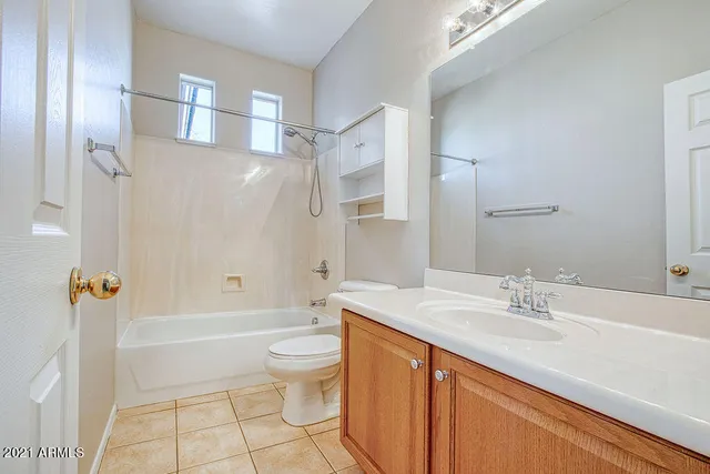 a bathroom with a granite countertop sink a toilet a mirror a bathtub and shower