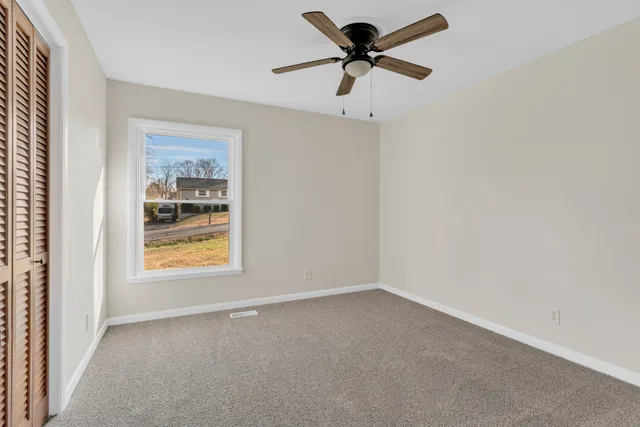 an empty room with a window and a fan