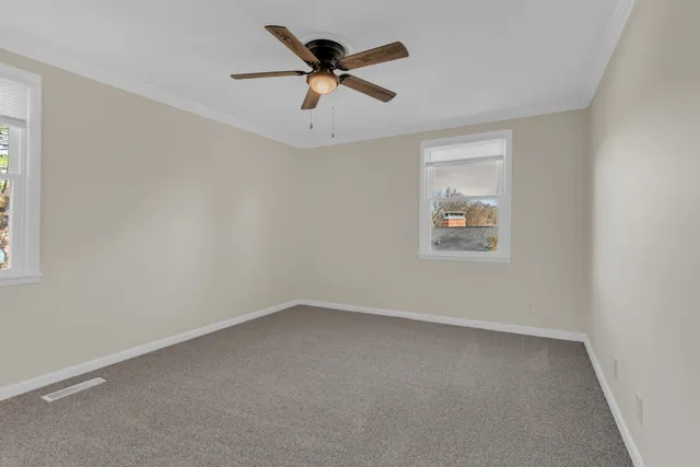an empty room with a ceiling fan and window