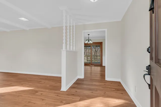 a view of a hallway with wooden floor and a room