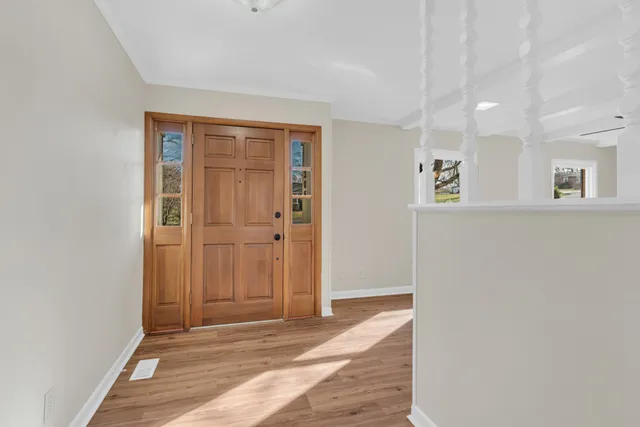 a view of a hallway with wooden floor and a bathroom