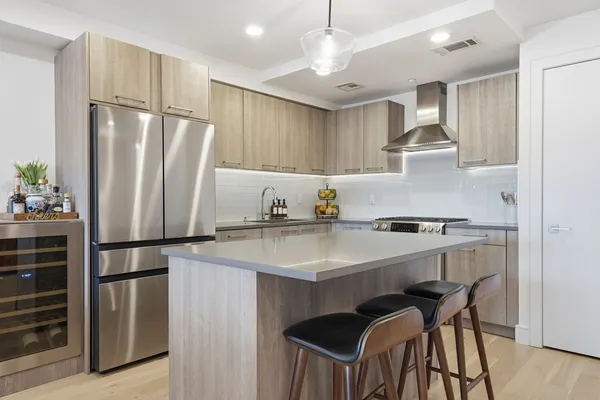 a kitchen with kitchen island granite countertop a dining table chairs and wooden floor