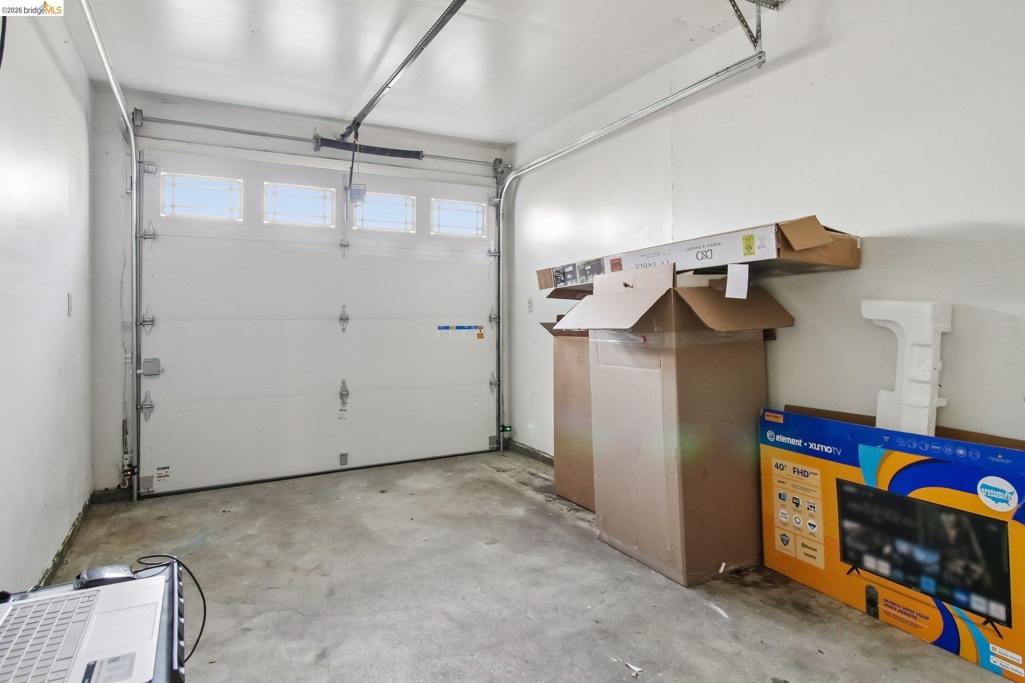 874 Pine Street Oakland, CA 94607 - Photo 23 of 39 Interior garage space featuring a white overhead door with upper window panels and a concrete floor