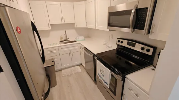 a kitchen with white cabinets and appliances