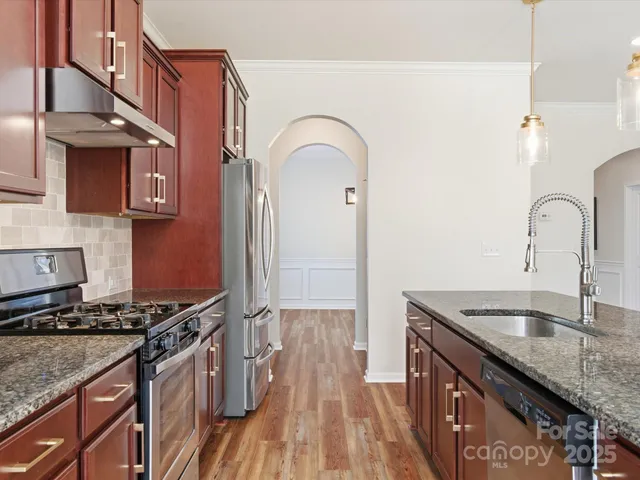 a kitchen with stainless steel appliances granite countertop a sink stove and cabinets