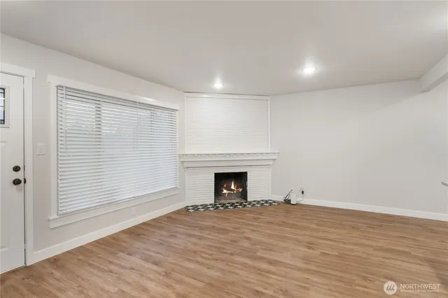a view of empty room with wooden floor and fireplace