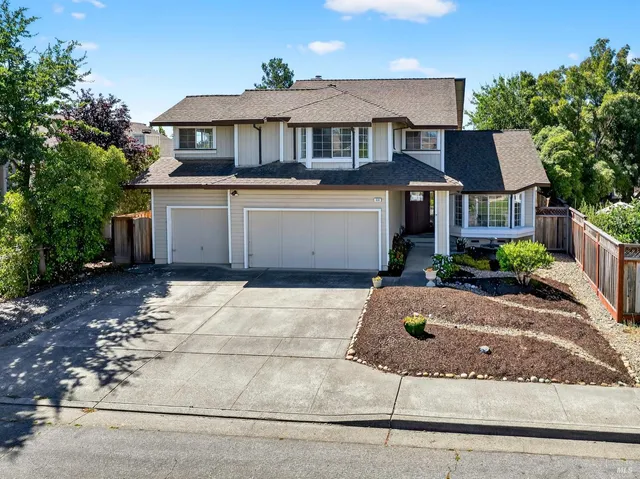 a front view of a house with garage and plants