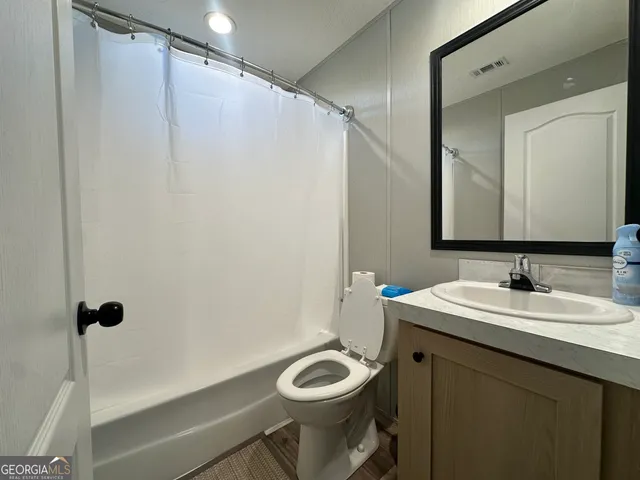 a bathroom with a granite countertop sink toilet and a mirror