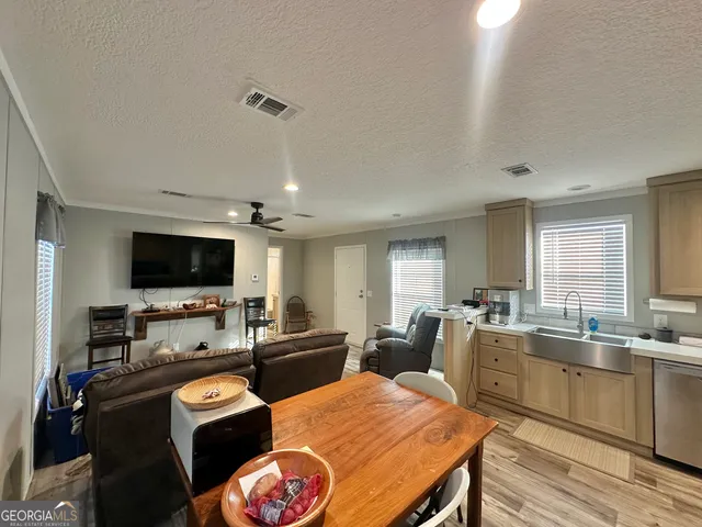a living room with furniture a flat screen tv and kitchen view