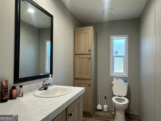 a bathroom with a granite countertop toilet a sink and a mirror