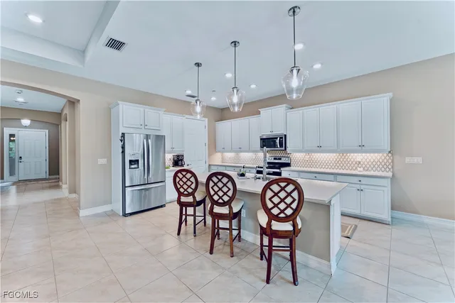 a kitchen with stainless steel appliances granite countertop a sink a stove a refrigerator and a dining table with wooden floor