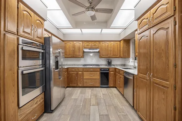 a kitchen with stainless steel appliances granite countertop a refrigerator and a stove top oven