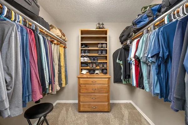 a view of walk in closet with clothes and shoes