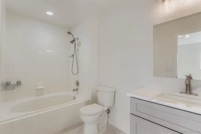 a bathroom with a granite countertop toilet a sink and a bathtub