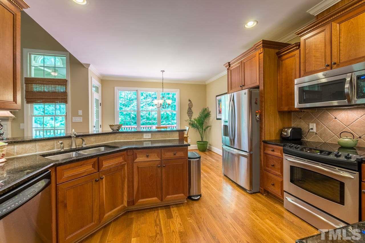 9512 Ray Road Raleigh, NC 27613 - Photo 7 of 25 a kitchen with granite countertop wooden floors stainless steel appliances a sink and a window