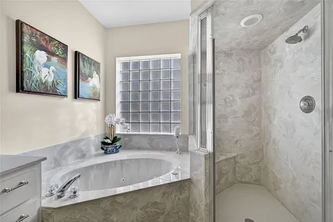 a bathroom with a tub a sink and glass door shower
