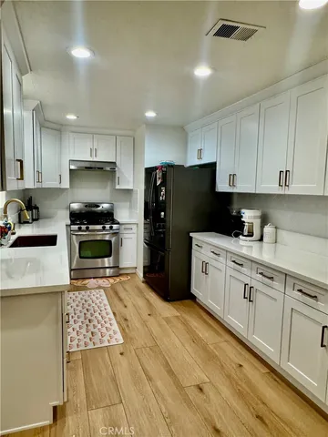 a kitchen with granite countertop a refrigerator stove top oven and cabinets
