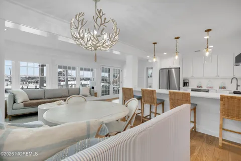 a kitchen with stainless steel appliances granite countertop a dining table chairs refrigerator and sink