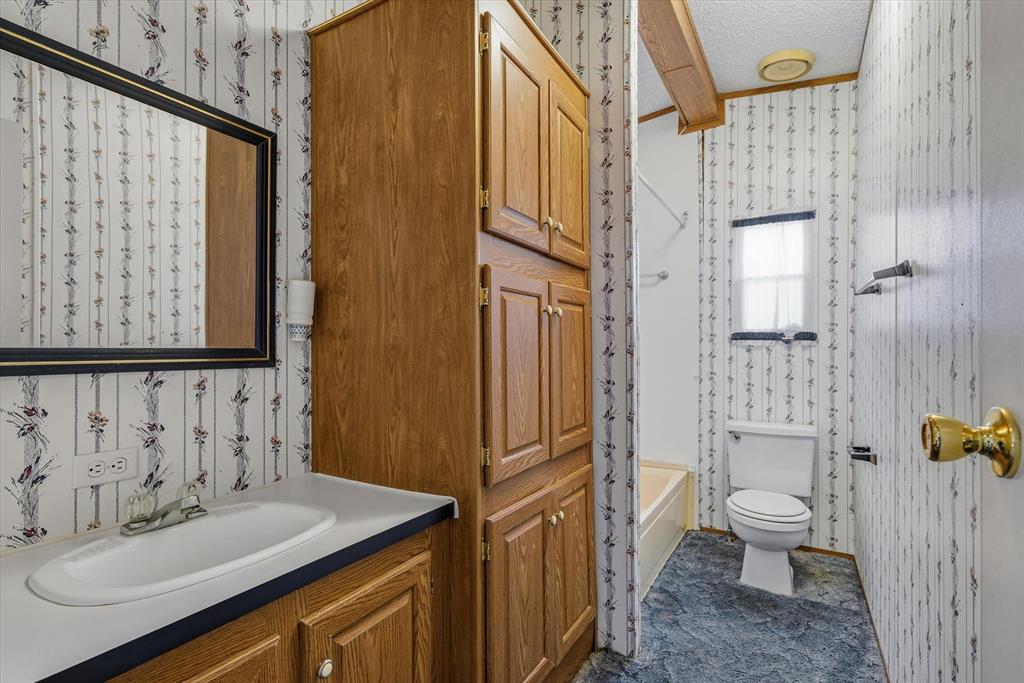 220 North Houston Street Edgewood, TX 75117 - Photo 20 of 30 a bathroom with a sink a toilet and shower curtain