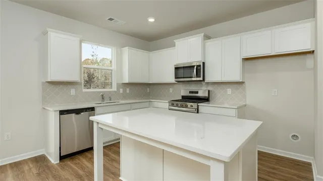a kitchen with a sink a stove a microwave and wooden floor