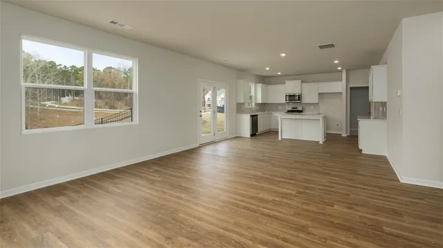 a view of a kitchen with kitchen island a counter top space a sink wooden floor and a large window