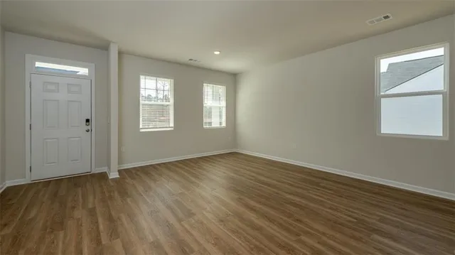 an empty room with wooden floor and windows