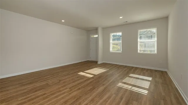 an empty room with wooden floor and windows